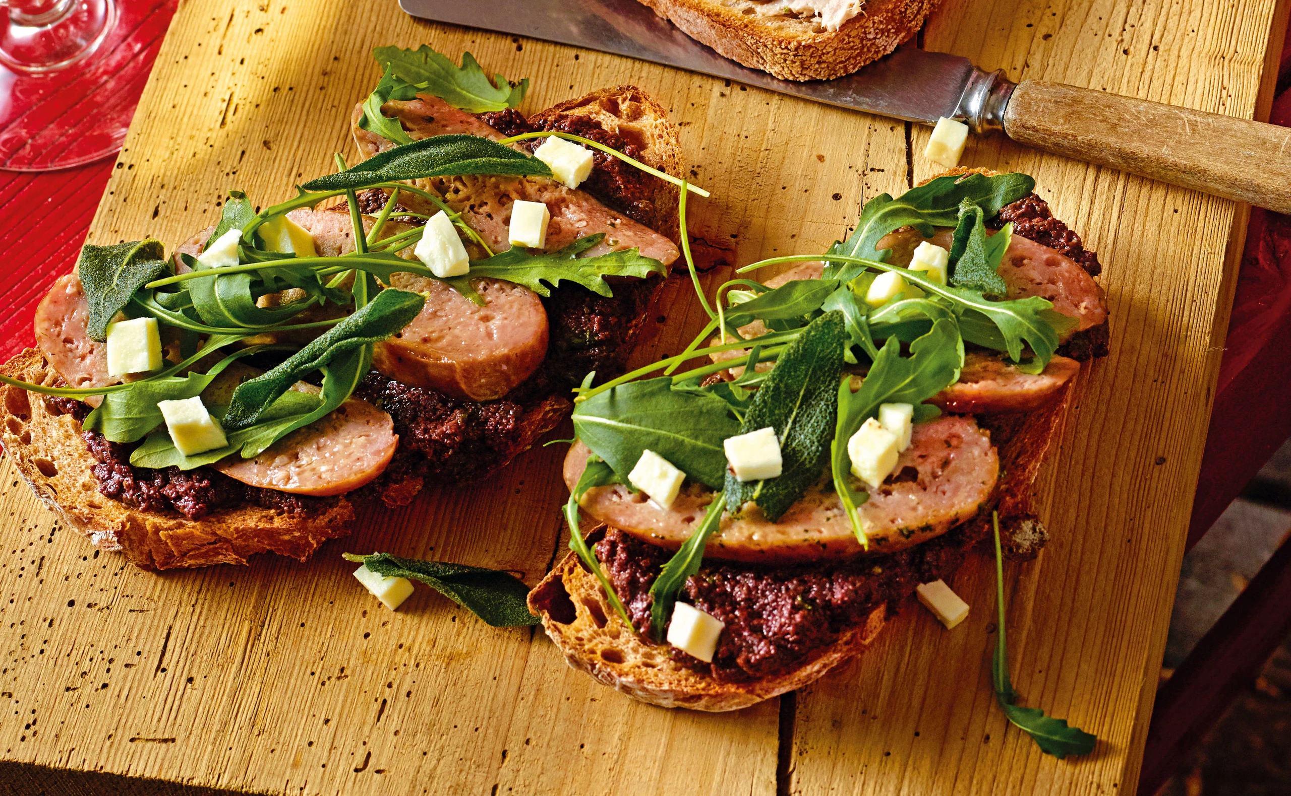 Brot mit Olivenpesto, Salsiccia, Mozzarella und Rucola